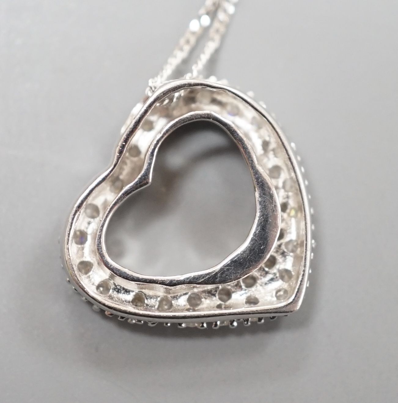 A modern 375 white metal and diamond chip set open work heart shaped pendant, 15mm, on a375 fine link chain, 40cm, gross weight 2.6 grams